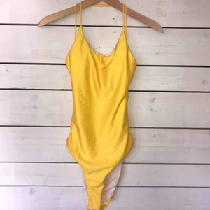  - Gul baddräkt med vadderade kupor. Öppen rygg med snörning, ej justerbar. Den är märkt som L men i verkligheten mer som en M.  Självfallet oanvänd