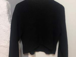En svart stickad tröja som är en aning croppad. Tröjan har vida armar och en allmänt skön passform. Väldigt skön för kalla vinterdagar:) 