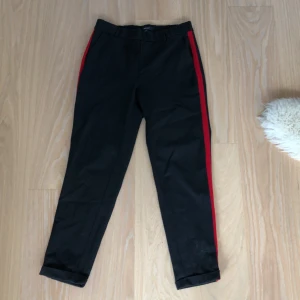 Kostymbyxor - Kostymbyxor med röd rand på vardera sida. Använda ett fåtal gånger. Storlek L, 34 i längd. Små i storleken så skulle passa M
