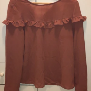 Blus från Vero Moda s.38 - En fin blus från Vero Moda med volang på framsidan. Färgen tas inte upp i kameran men en gammaldags rosa med lite brun underton. Köpt för ett år sedan, använd 1 gång. Blusen är i s.38 & är köpt för 300kr. Mitt pris är 100 + frakt 44kr.  Budgivning sker i kommentarerna.