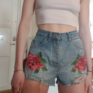 Jeansshorts  - Jeansshorts med fastsydda blommar på framsidan. Från Zara, bra skick.  (Har justerat byxorna så de ska se ut som de gör när de passar. De är alltså för stora för mig egentligen) Frakt tillkommer, kan även mötas upp i Stockholm.