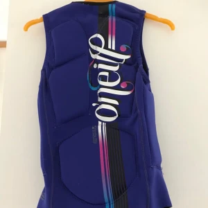  - WMS GOORU PADDED VEST, Impact-flytväst från oneill som dras över huvudet, figurnära och mycket smidig. Går att använda både med lila sidan och rosa sidan utåt.