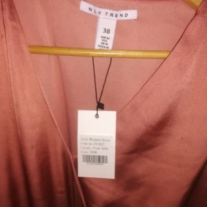  - En rosa satin klänning från Nelly.com  Den är helt oanvänd och Prislappen sitter kvar.  Har du några frågor eller vill se mer bilder så är det bara att fråga