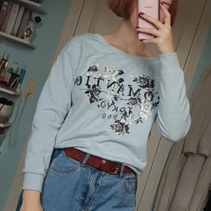  - Ljusblå sweatshirt med stort tryck på framsidan