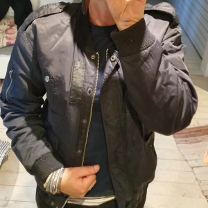 Bomberjacka  - Snygg bomberjacka från Cubus stl 36. Snygga detaljer med vinrött innerfoder. Fint använt skick! 