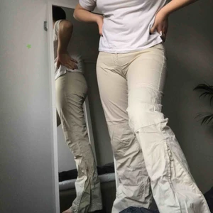  - Ett par beigea byxor, dragkedja längst ner där en kan välja att ha bootcut eller inte. Köpta second hand. 