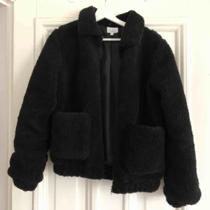  - Svart teddyjacka från NA-KD stl 34. Jättefint skick, använd ca 5 gånger. Perfekt som vårjacka då den värmer lagom mycket! Köpt för 699 kr. Köparen betalar frakten. Kom gärna med bud! 