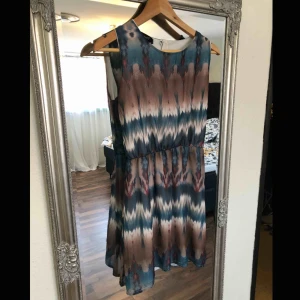  - Klänning med fint mönster och ”gummiband” i midjan. Klänningen är kort.