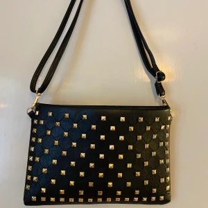 Väska med nitar - En väska med guldiga nitar som jag köpte när jag var utomlands. Den är sparsamt använd och i felfritt skick! 