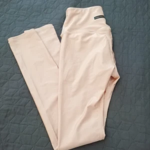 Asos träningstajts - Yogatajts/gymtajts köpta på Asos i mycket gott skick, aldrig använda. Hög midja, Stl S men drar åt det mindre. Ljusrosa med pärlemor skimmer, nästan som tjockt badräktsmaterial. Extra tyg inuti vid rumpan. Dom är mer rosa än bilden visar