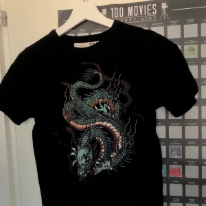 T-shirt med draktryck  - Köpt från junkyard, är liten i strl så sitter mer åt XS hållet. Frakt ingår 