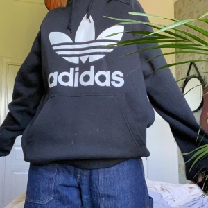 Svart adidas hoodie - En fin svart adidas hoodie! 💕Den är väldigt mjuk och bekväm, jag har använt den ett fåtal gånger. Den är i bra skick men det går ett streck genom loggan. Frakt tillkommer 😊