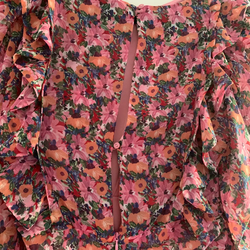 Blommig klänning köpt i våras för 399 kr. använd vid 1 tillfälle på en examen och säljs därför. Den är blommig i rosa orange grön och är draperad på ena sidan framtill. Också är det puffiga armar och volanger. Baksidan har delvis öppen rygg se bild 3. Klänningar.