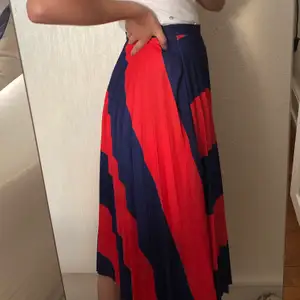En röd och blå randig, plisserad kjol från bershka! Endast använd en gång. Köpt i spanien men kommer inte till användning