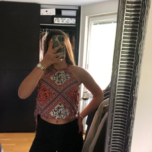 Multifärgad top - Fint mönstrad top med knyte på sidorna och knäppning med en knapp vid nacken. Hur nice som helst till en grillkväll. 🧡💙🤍