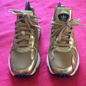  - Guldfärgade sneakers med lila, blå och röda detaljer på sulan. Adidas Falcon. Använda en gång, så i bra begagnat skick! 200 plus frakt. 