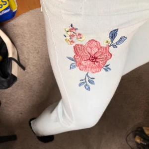 Ljusblåa jeans med blommor på - Dem ser lite konstiga ut på bilden då dem är försmå för mig.