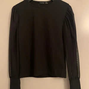 Topp med armar i meshtyg - Svart topp med armar i meshtyg från Boohoo. Storleken är 42 men skulle säga att den passar S/M. Köparen står för frakt.