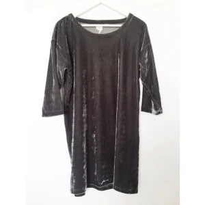  - Sammetsliknande material. Trekvart-ärmar och knälång (på mig som är 164cm). Den är enfärgad i grått, kanske ser lite randig ut på bilden men materialet glänser lite i ljuset. Superfin! 