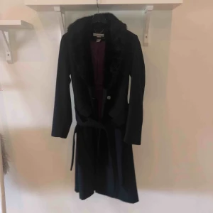  - Svart kappa med fusk päls och en lila fordring, använd 1 gång och köpt i USA. Nypris 1199:- 