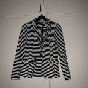  - De är en randig kofta från New Yorker  som har blivit använd en gång tidigare, den har två små fickor fram och en knapp i mitten, kappan är v ringad hela vägen till knappen. 