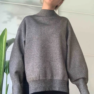  - Grå-glittrig tröja från H&M. Slits på sidan. Mycket skön! Inga skador, mer eller mindre i nyskick. Eventuell frakt tillkommer, möts annars upp i centrala Stockholm 