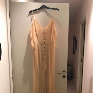  - Finklänning, persika färgad. En sommarklänning perfekt för bröllop eller finare tillställningar. Plagget har aldrig använts. Klänningen är köpt från Nelly. 