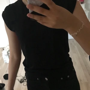 T-shirt  - En svart T-shirt men diamant detaljer vid axlarna. Det står att den är i storlek M men passar en XS/S