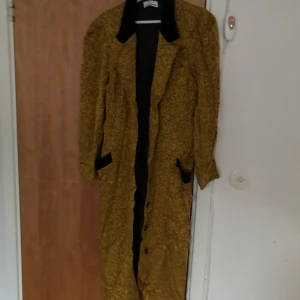 Kappa från Birgitte Haarke - Lång kappa i gul-guldig färg med svarta detaljer. Köpt på second hand. Måste sälja den är för liten på mig :( 
