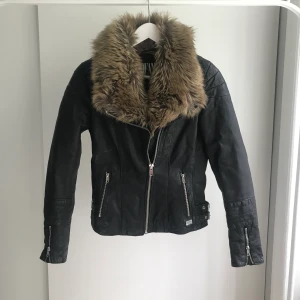 Skinnjacka Jofama by Kenza - Äkta skinnjacka med krage av fejkpäls designad av Kenza för Jofama. Storlek 34. Lite skada i innertyget (sprucken söm, se bild) som enkelt går att laga. Nypris ca 3000kr