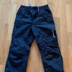  - Svarta Didriksson överdragsbyxor i nyskick, vind och vattentäta i storlek 130.