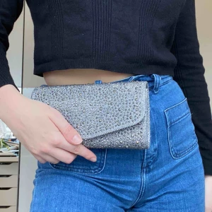  - Glittrig silver clutch från en butik i USA. Aldrig använd och i bra skick. Skriv för mer info/bilder, frakt tillkommer.