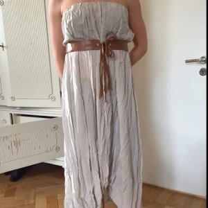  - Tunn, lång, nudefärgad klänning. Resåret upptill och skärpet i fuskläder har åldrats något, där av det låga priset. Passar en XS-L beroende på hur man vill att den ska sitta.