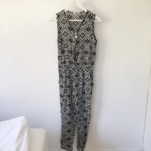  - Svart och vitmönstrad byxdress. En stor dragkedja som urringning, går att dra upp och ned.