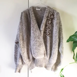  - Vintage kofta med broderade detaljer och omlott urringning. Materialet är en blandning av silke och angora. Frakt ingår i priset.