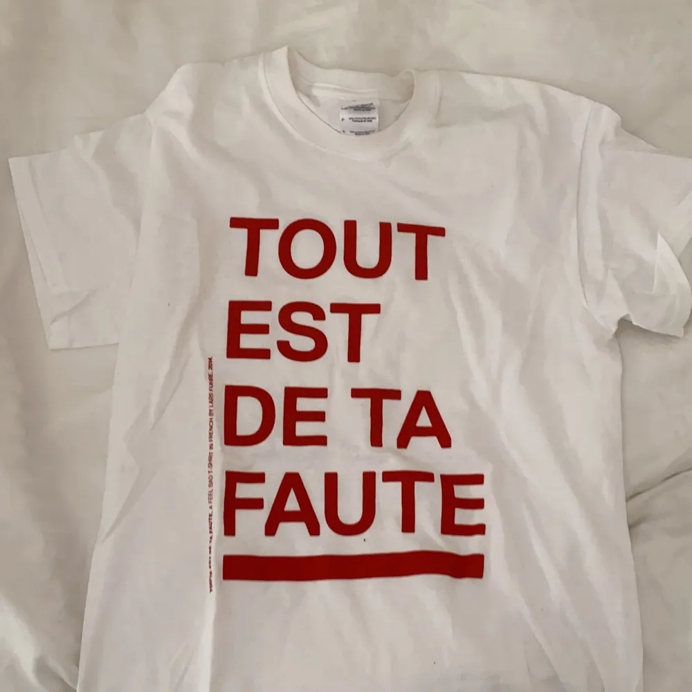 Fin tshirt med fransk text där det står ”allt är ditt fel. Gjord av konstnären Lars Fuhre. Aldrig använd.. T-shirts.