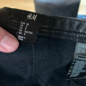 Kjol - Svart läderkjol (ej äkta) med mindre slits baktill. 