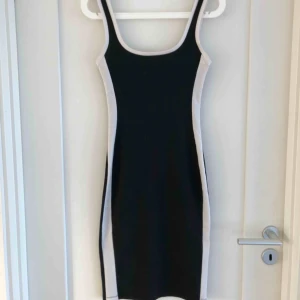  - Svart knälång klänning med skulpterande vita detaljer från Zara. Storlek S.