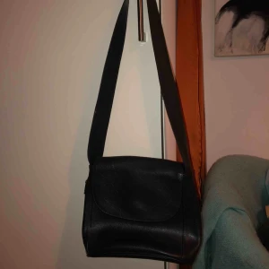  - Mörkblå/ svart axelremsväska i skinn imitation! Köpt från second hand i Finland, fint skick.   Fraktar eller möts upp på gullmars eller söder. Köparen står för frakt.