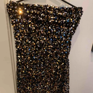  - Tibklänning i guld, svart -och silverpaljetter, använd en gång.