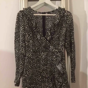  - Jättefin svartvit prickig med volang i kjoldelen som går upp till axlar och urringningen. Väldigt djup urringning( kan ordnas med nål/tråd), dragkedja bak. Blankt och glattigt tyg. Ca 5-10 cm ovan knä ( jag ör 159,5 cm) Använd 1 gång.