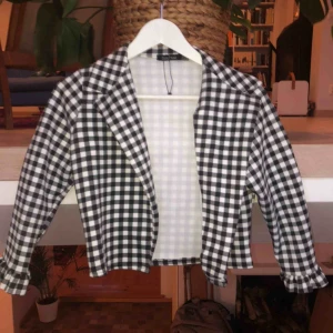  - En croppad jacka med trekvartsarmar i mjukt material, aldrig använt 