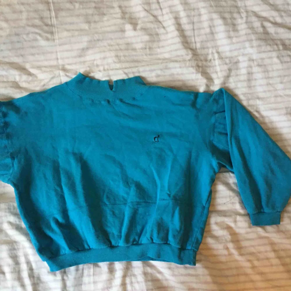 Blå sweatshirt med en liten turtleneck. Köpt second hand och i använt skick. Sömmen mitt på tröjan har gått upp lite grann men det är inget som märks eller gör skillnad! . Tröjor & Koftor.