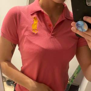 Rosa Ralph Lauren T-shirt. Köpt begagnad, tvivlar på att den är äkta, men det är väldigt bra kvalite och detaljerad för att vara en kopia isåfall. Säljer för att den sitter för tajt i armhålan på mig. 