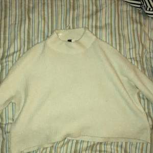 En vit långärmad stickad tröja som även är lite cropad vid magen