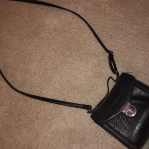 Liten hand/axel väska - Liten handväska/axelväska med långt band, använd några gånger, ett litet skrap på framsidan av väskan på silverknappen, annars inga skador alls.