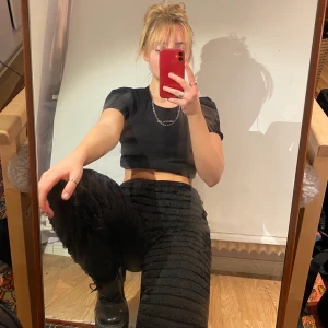 Byxor m. Volang! - Svarta tightsliknande byxor med volanger längs framsidan i ett väldigt finmaskigt material. Coola till boots el liknande!        Obs!! Baksidan är _inte_ läderimitation, det är vanligt svart stretchtyg.