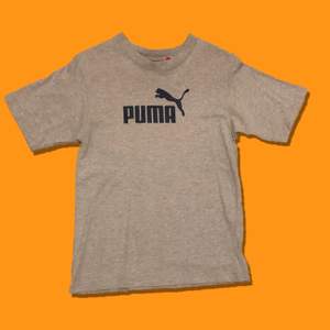 Vintage Puma logo-tee.                                                   Färg: Grå/Mörkblå.                                                     Skick:8/10 inga fläckar/hål.                                    Storlek:Boys M (liten storlek).  Pit to pit:40cm                                                                            KÖP NU: 100kr. Frakt tillkommer (63kr).                        