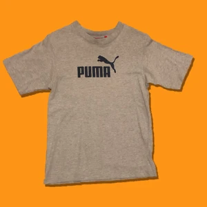Vintage Puma logo-tee - Vintage Puma logo-tee.                                                   Färg: Grå/Mörkblå.                                                     Skick:8/10 inga fläckar/hål.                                    Storlek:Boys M (liten storlek).  Pit to pit:40cm                                                                            KÖP NU: 100kr. Frakt tillkommer (63kr).                        