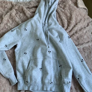 Hoodie från HM - Grå hoodie med mussepigg tryck. Storlek S och super super mysig. Använd ett fåtal gånger. Fint skick.